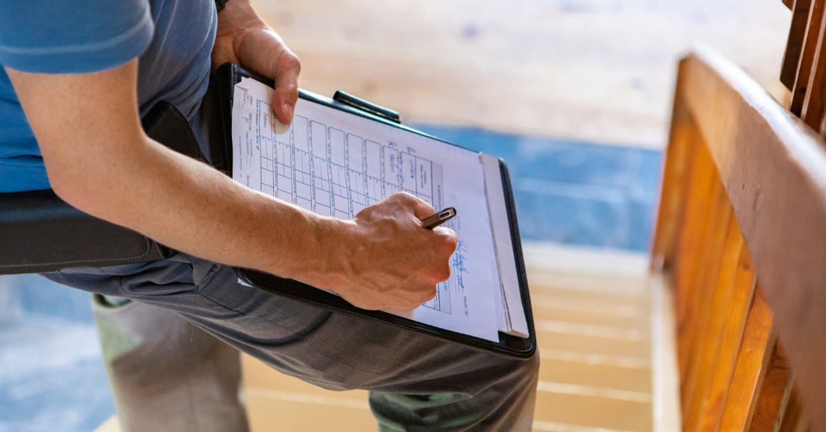 A person is standing on the stairs, writing on a piece of paper that sits on a clipboard. They're using a leg as a table.
