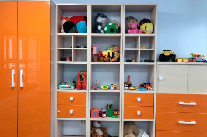 A kids’ closet with multiple square compartments for toys, two large orange doors, and multiple drawers on the side.