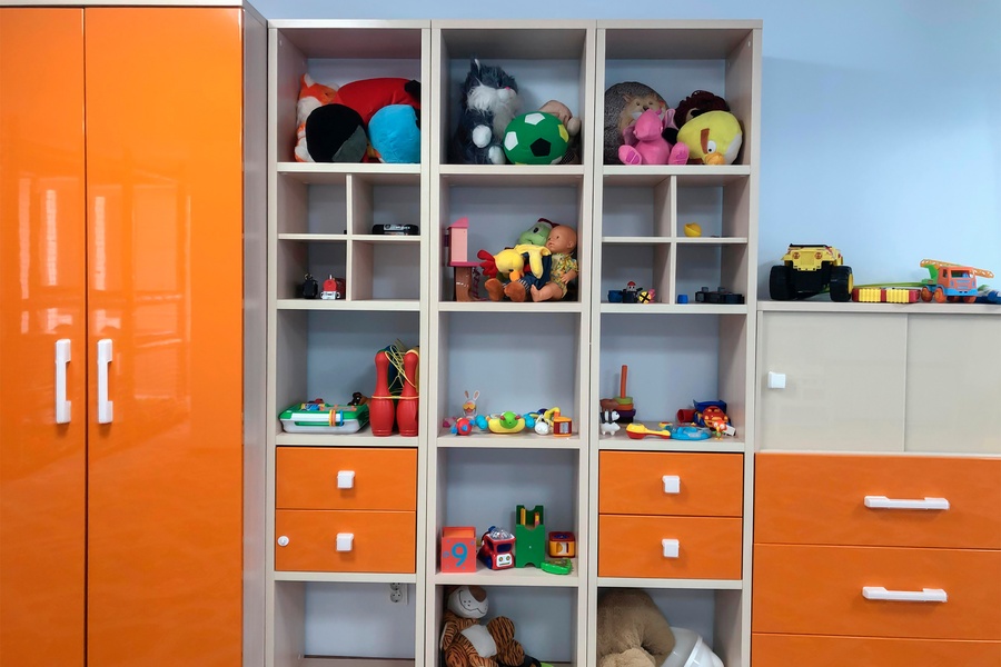 A kids’ closet with multiple square compartments for toys, two large orange doors, and multiple drawers on the side.